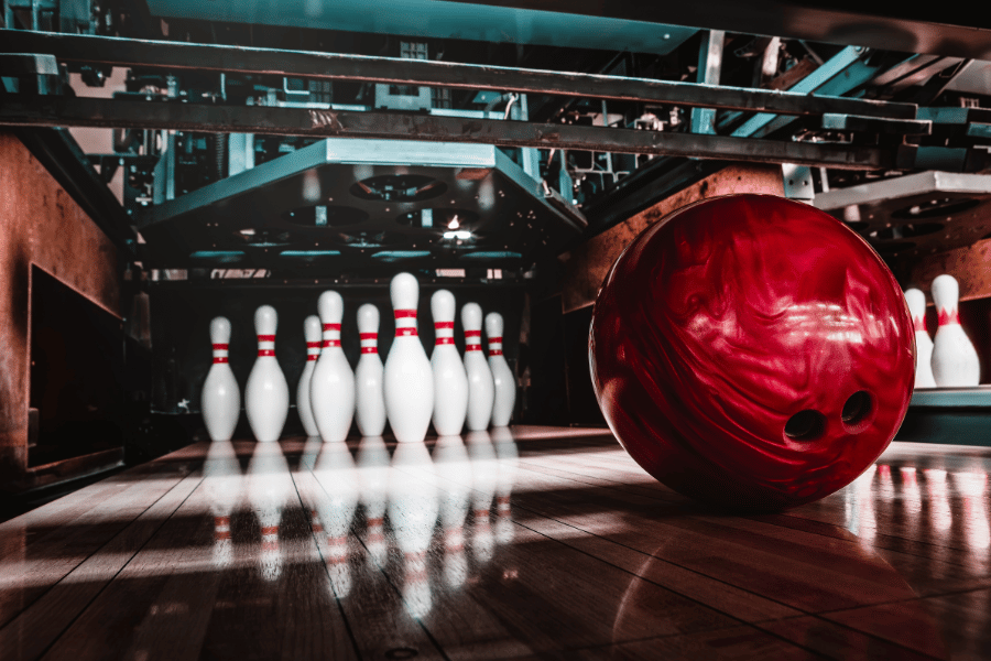 Bowling ball in a bowling lane about to knock over pins