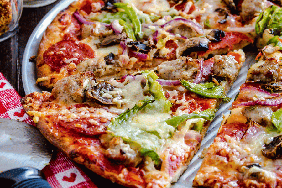 Thin crust pizza on table with meat and vegetables 