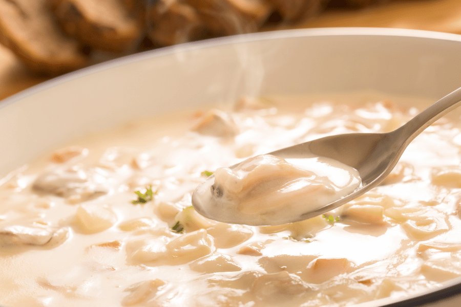 New-England-clam-chowder.png new england clam chowder in a bowl with spoon